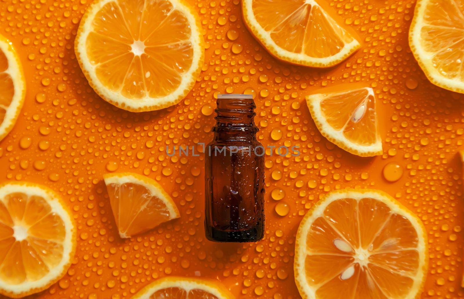 Bottle of cosmetics and drops of liquid, moisturizing orange. Hyaluronic acid. Selective focus. Spa.