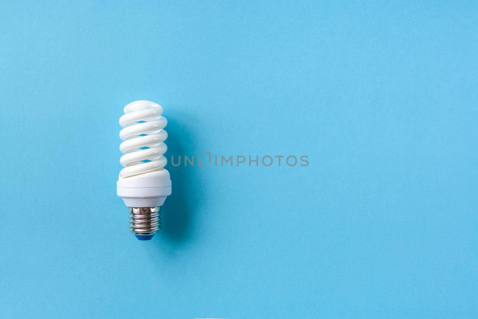 Energy saving light bulb on a blue background. Economical consumption of electricity. The concept of nature conservation