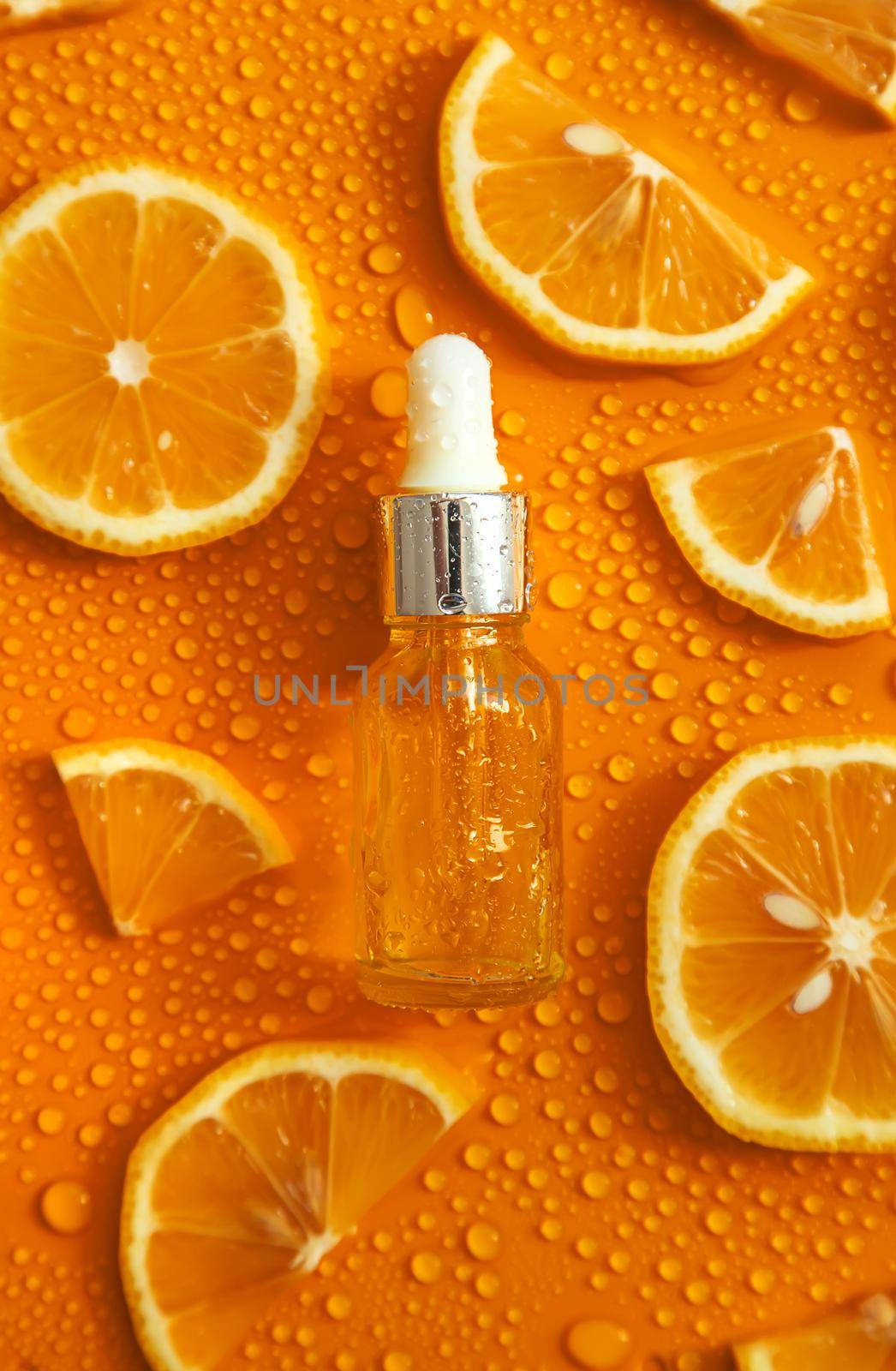 Bottle of cosmetics and drops of liquid, moisturizing orange. Hyaluronic acid. Selective focus. by yanadjana