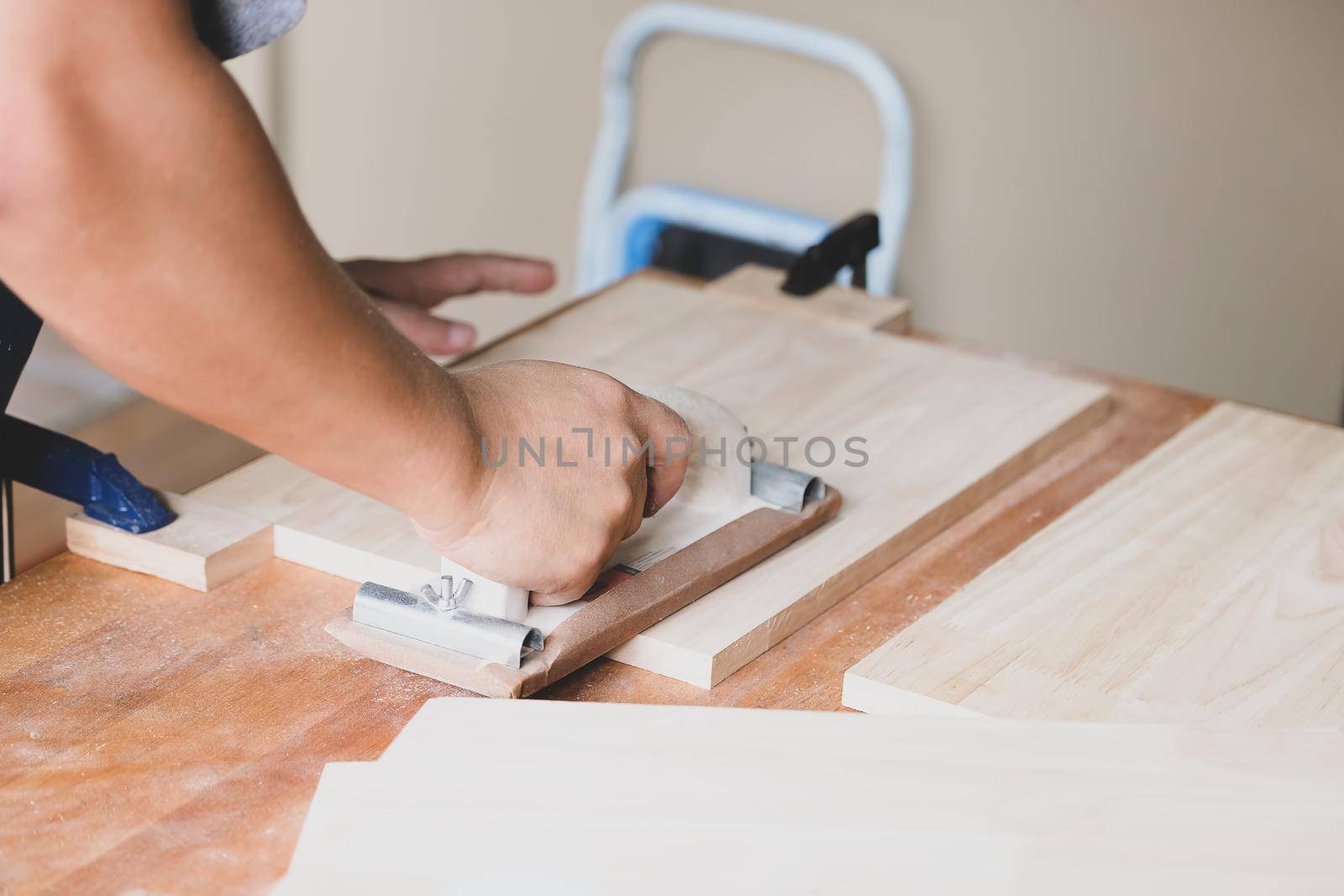 Woodworking entrepreneurs are using sandpaper to decorate wooden pieces to assemble and build wooden tables for their clients. by Manastrong