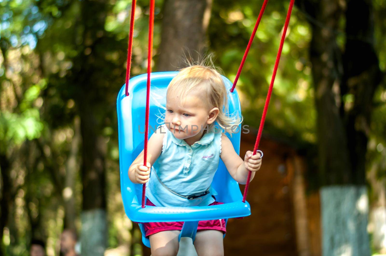 toddler girl on a swing in the park. High quality photo
