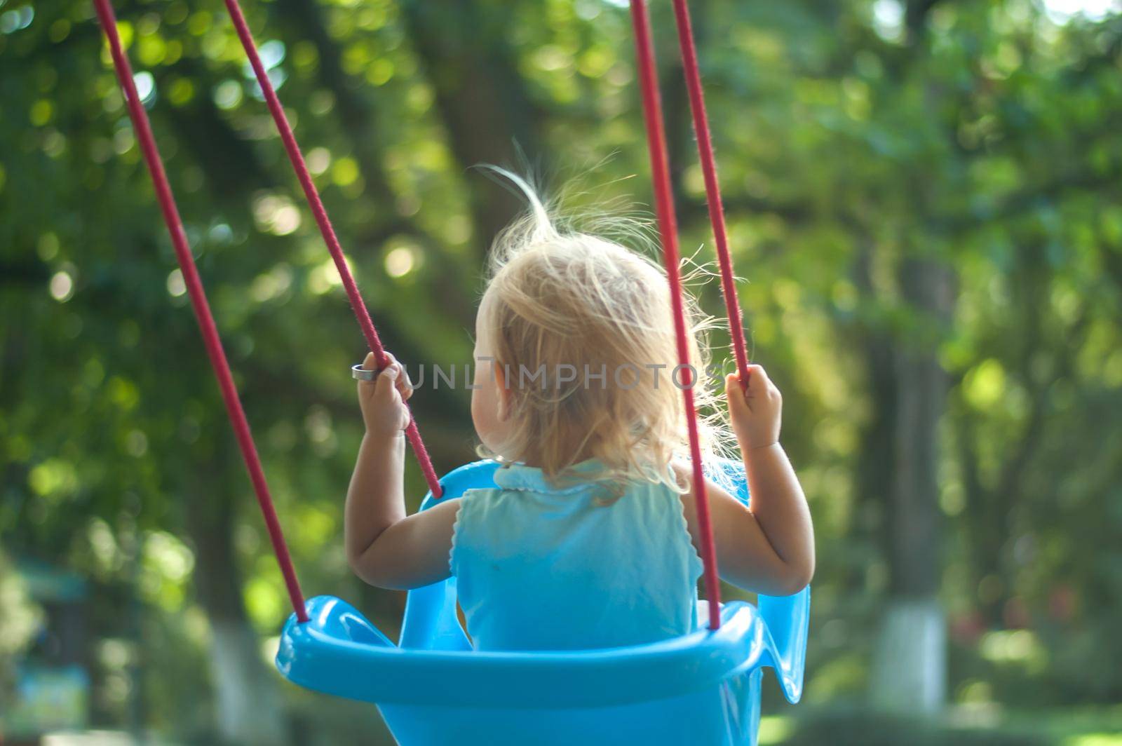 toddler girl on a swing in the park. High quality photo