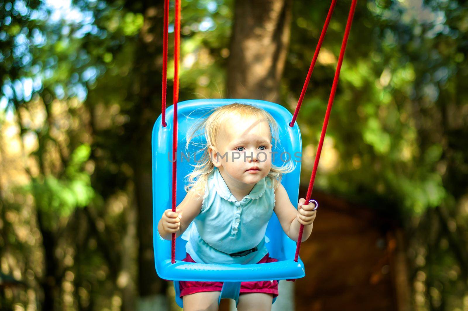 toddler girl on a swing in the park. High quality photo