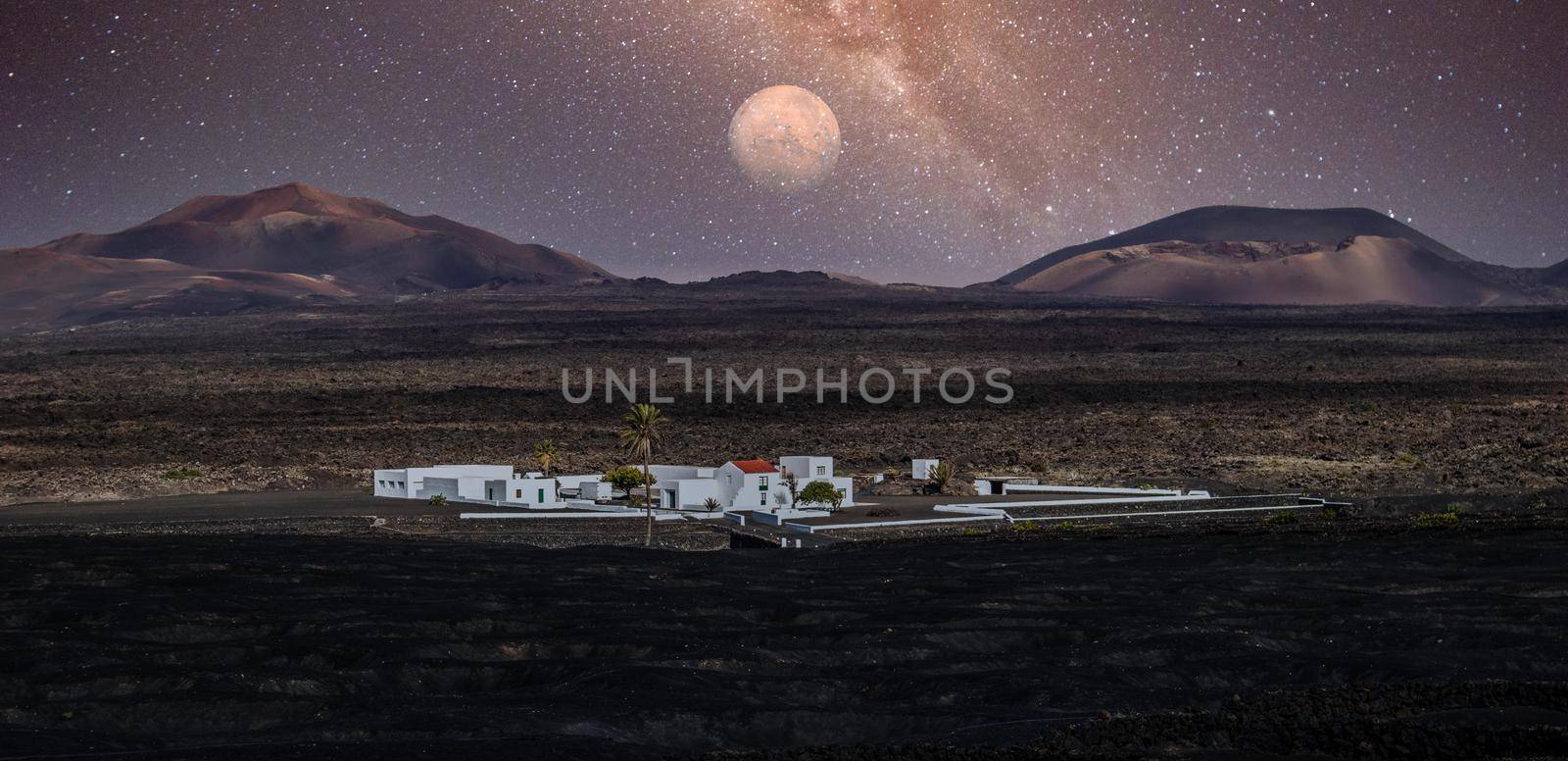 Amazing nocturnal panoramic landscape of volcano craters in Timanfaya national park. Full moon over La Gueria, Lanzarote island, Canary islans, Spain. Artistic night sky picture.