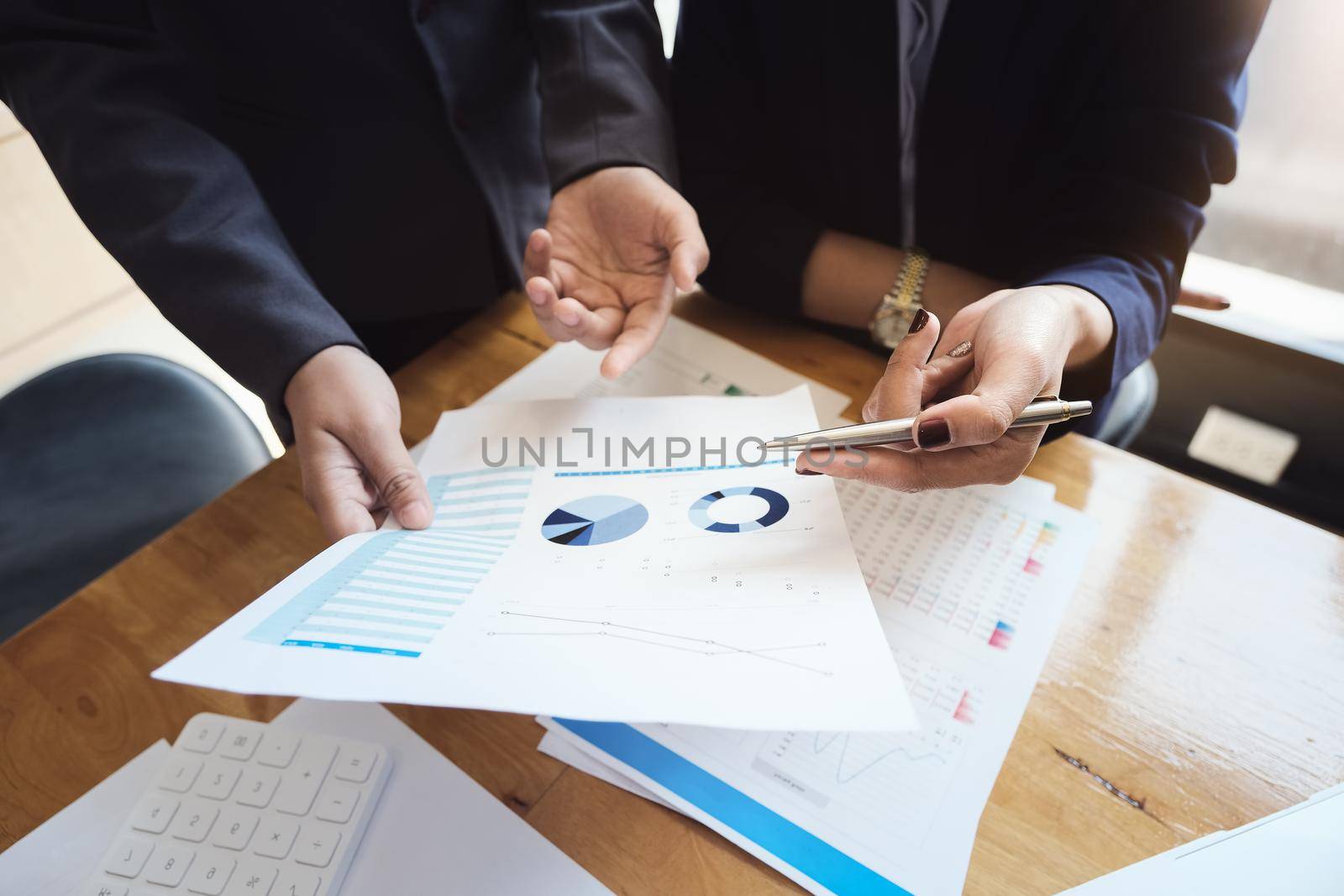 An auditor holds a pen pointing to documents to examine budgets and financial fraud