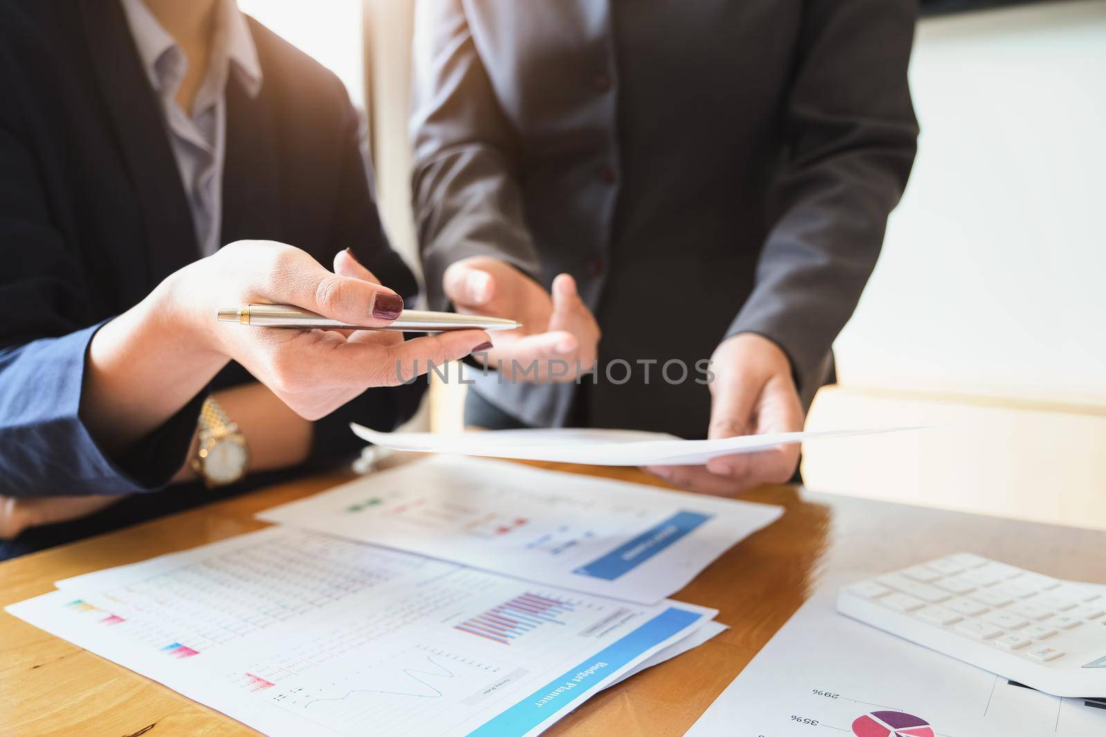 An auditor holds a pen pointing to documents to examine budgets and financial fraud. by Manastrong