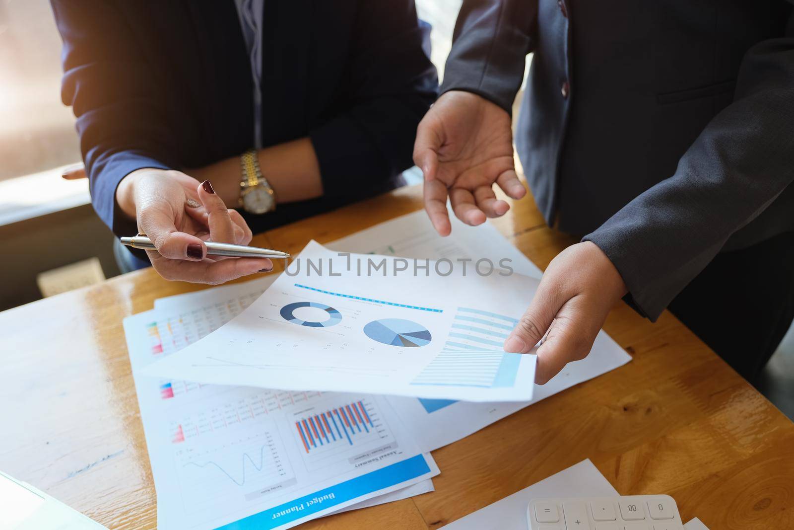 An auditor holds a pen pointing to documents to examine budgets and financial fraud. by Manastrong