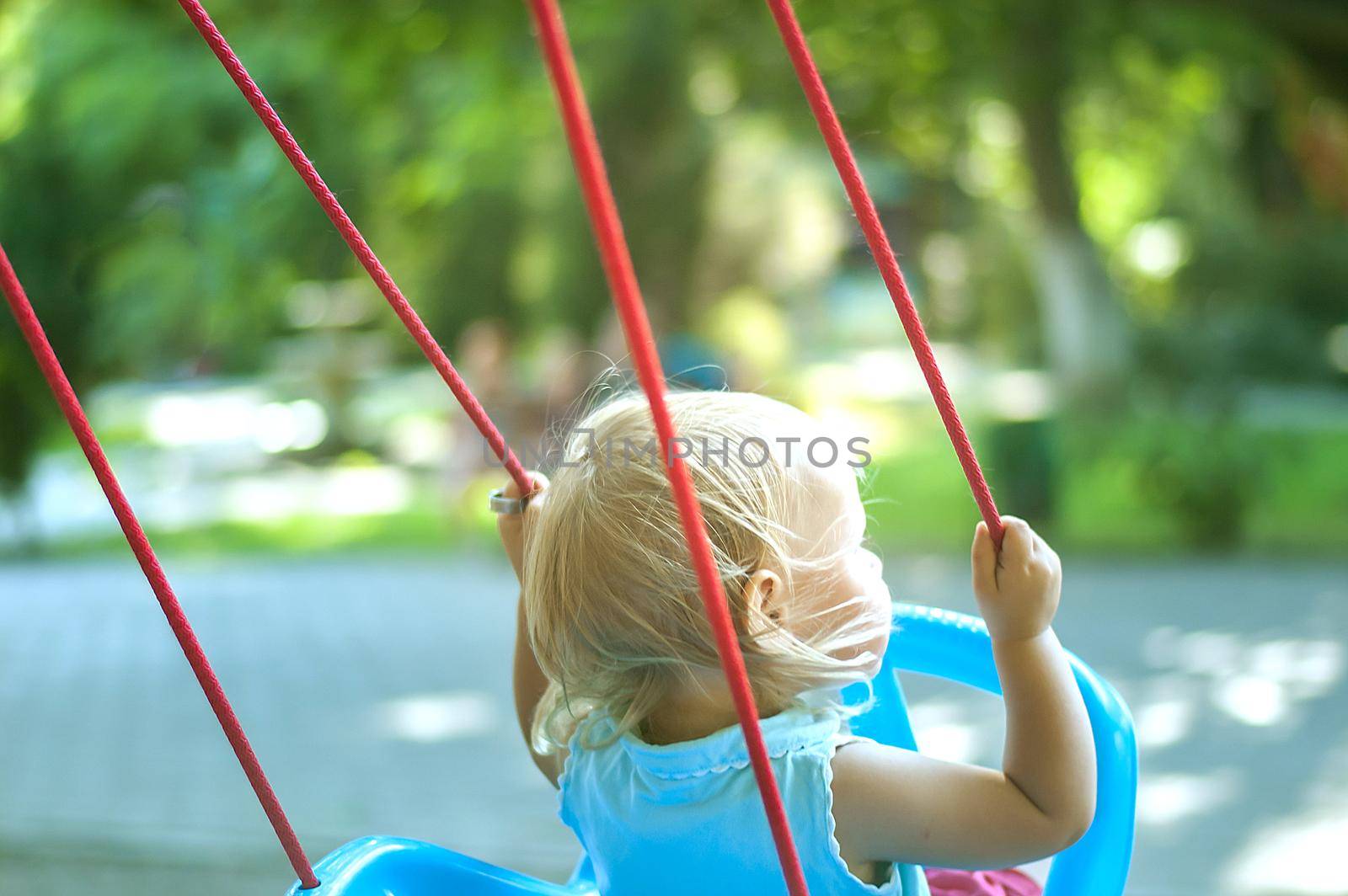 toddler girl on a swing in the park by maramorosz