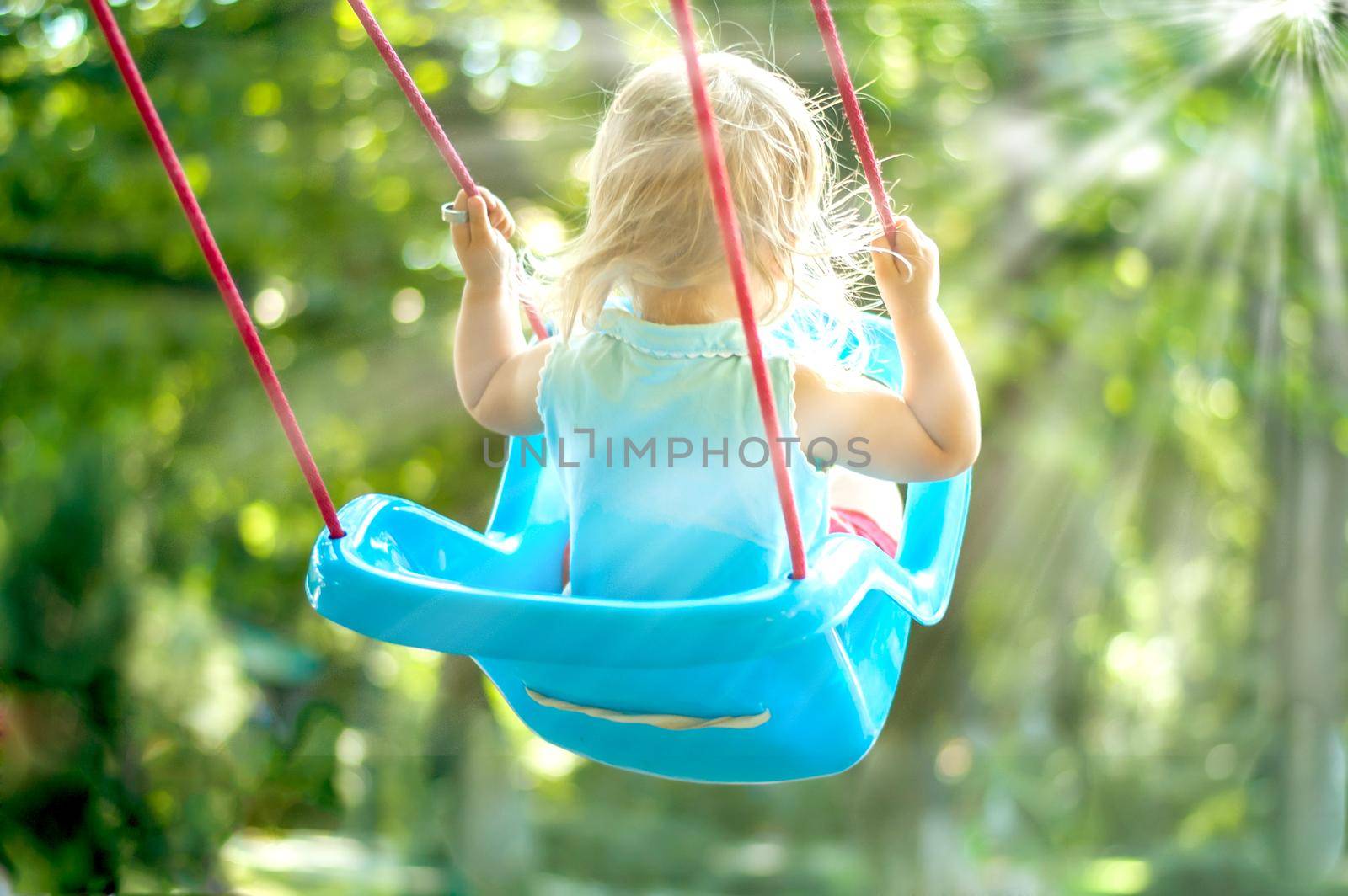 toddler girl on a swing in the park by maramorosz