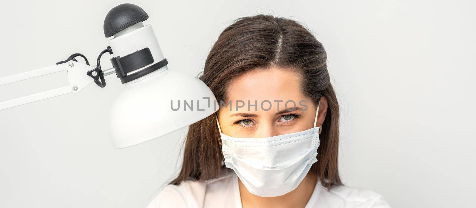 Portrait of manicure master with white protective mask working in beauty salon