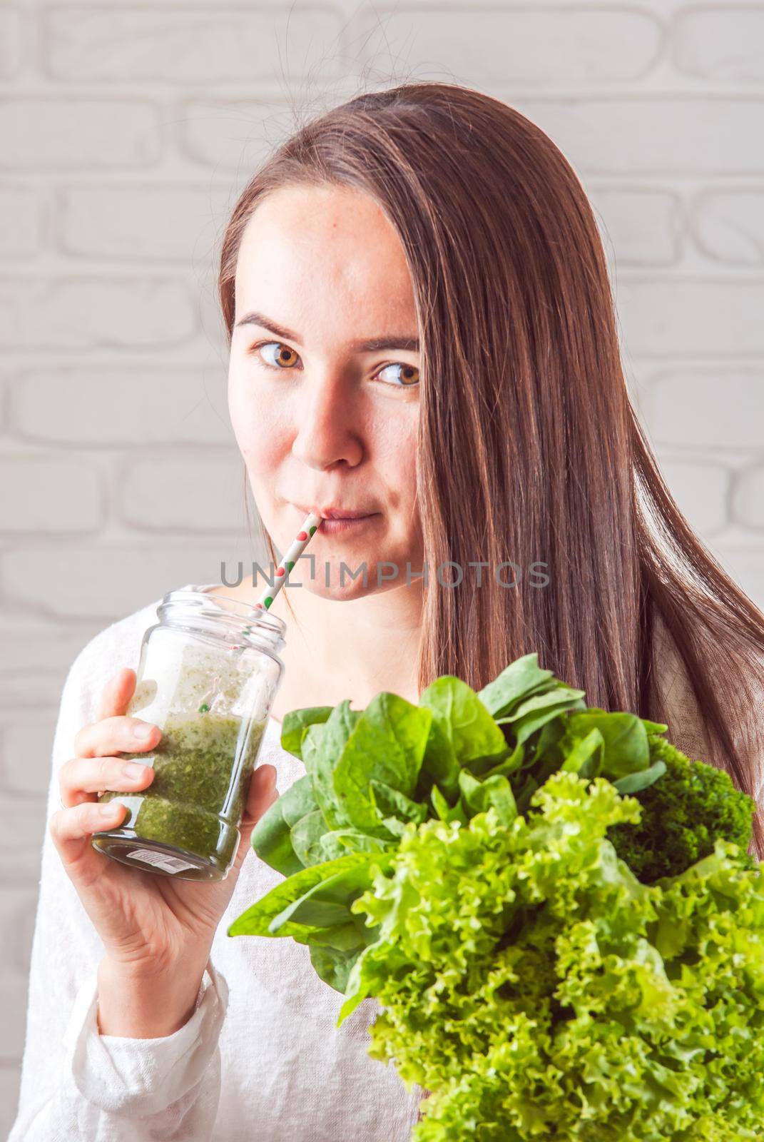 beautiful young smiling woman is drinking green detox shake . High quality photo