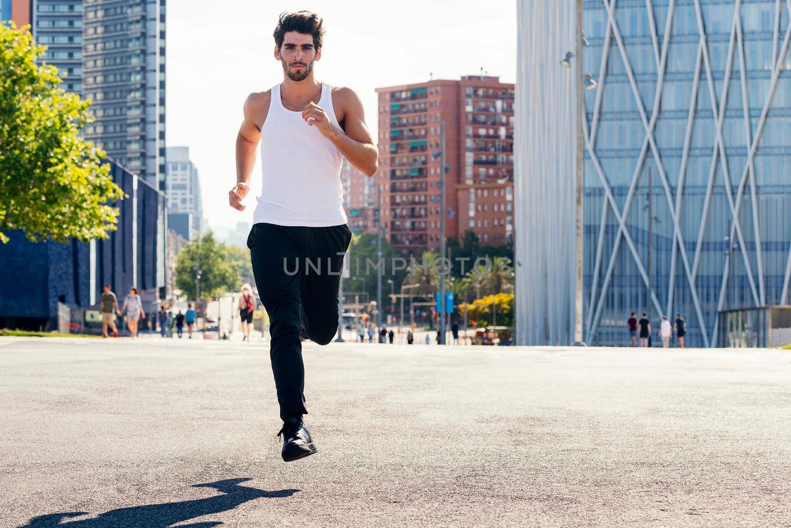 front view of a sporty man running on the asphalt in the city, concept of urban sport and healthy lifestyle, copy space for text