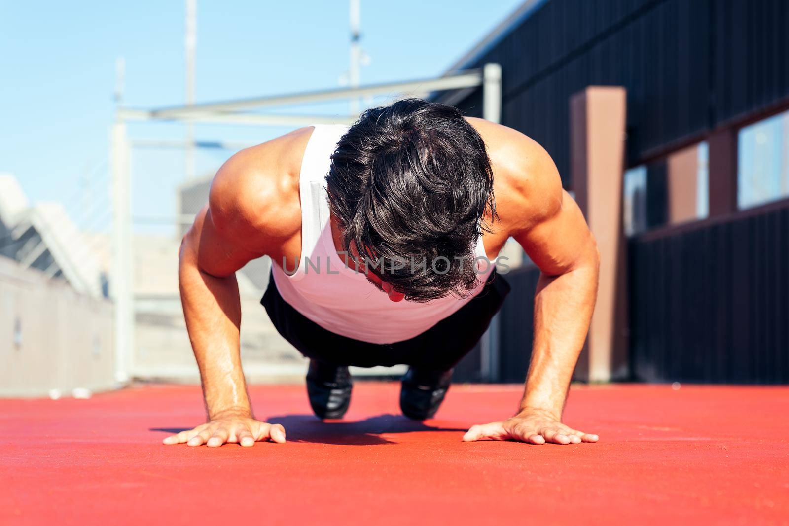 unrecognizable sporty man doing push ups on a red floor, concept of urban sport and healthy lifestyle