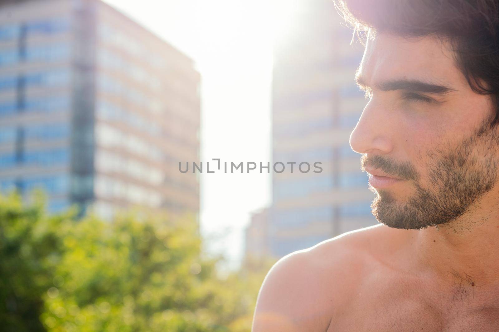 profile portrait of a handsome shirtless sporty man at sunset in front of city buildings, concept of urban sport and healthy lifestyle, copy space for text