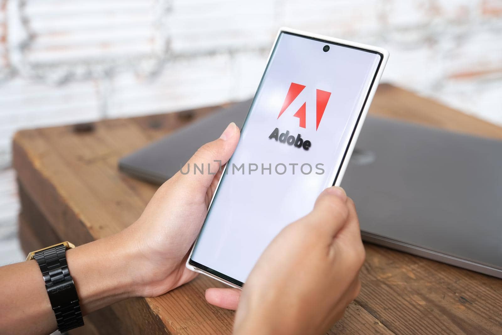 Chiangmai, Thailand, June 06, 2021: woman holding smartphone mobile show Adobe logo on the smartphone screen.