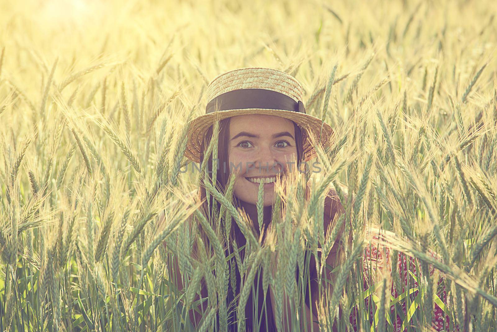 young woman in straw hat in the middle of wheat field
