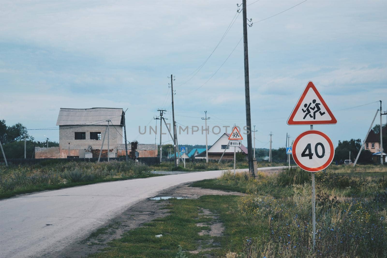 Speed limit sign and pedestrian signs against the backdrop of a rural landscape in Russia by ProjectStockman