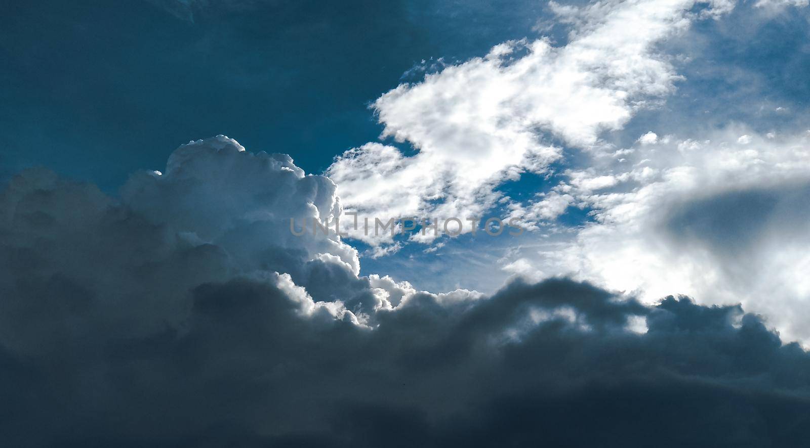 The formation of a cumulus cloud lit by the sun against the background of clouds and blue sky by ProjectStockman