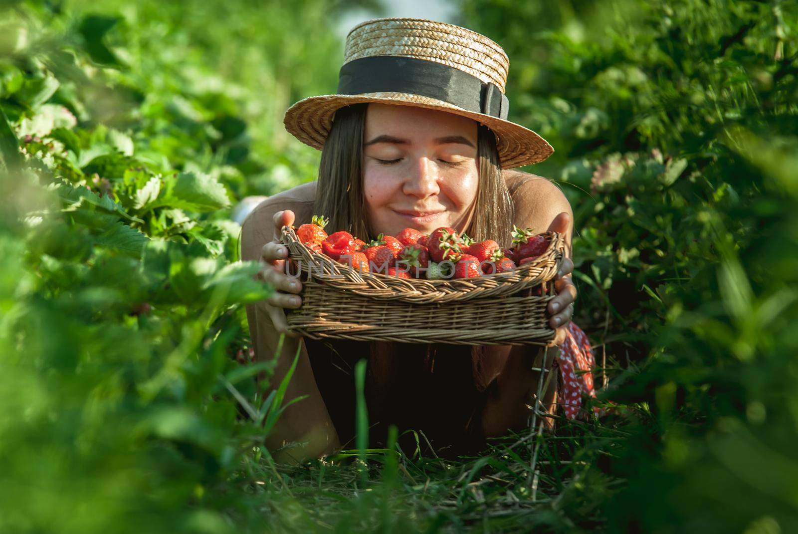 girl in strawberrry field with basket of fresh picked fruits