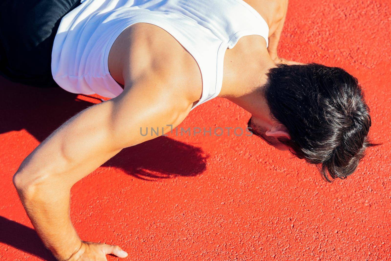 close-up of an unrecognizable sportsman doing push-ups on a red floor, concept of urban sport and healthy lifestyle