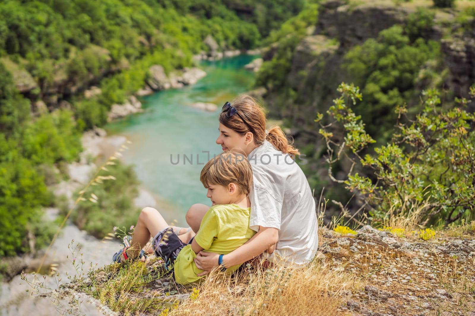 Mother and son tourists on background of purest waters of the turquoise color of the river Moraca flowing among the canyons. Travel around Montenegro concept by galitskaya