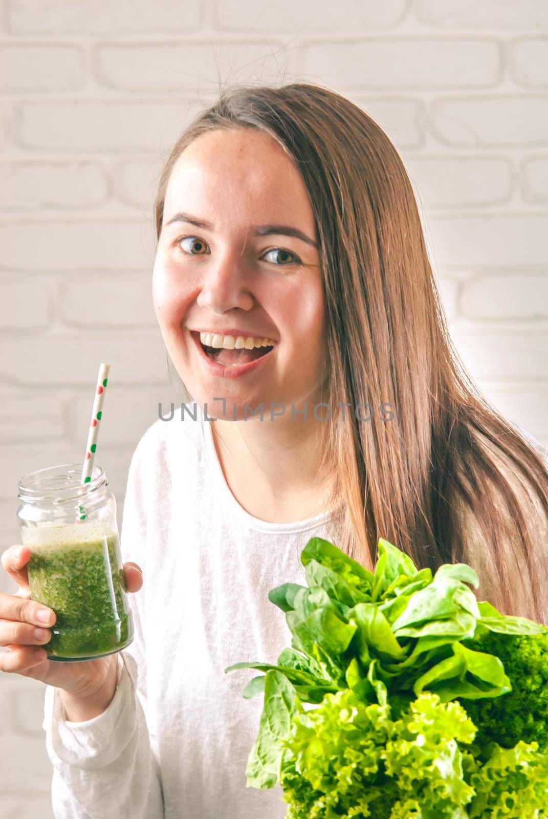 beautiful young smiling woman is drinking green detox shake . High quality photo