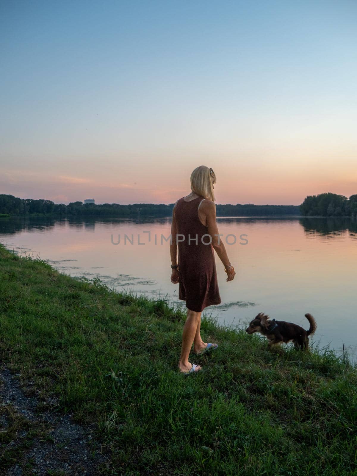 Beautiful woman enjoys holidays at sunset near river