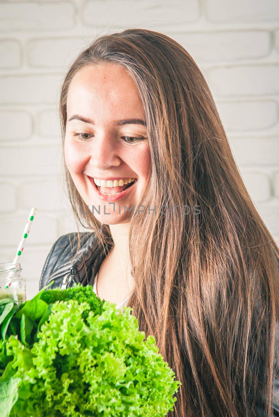 beautiful young smiling woman is drinking green detox shake . High quality photo