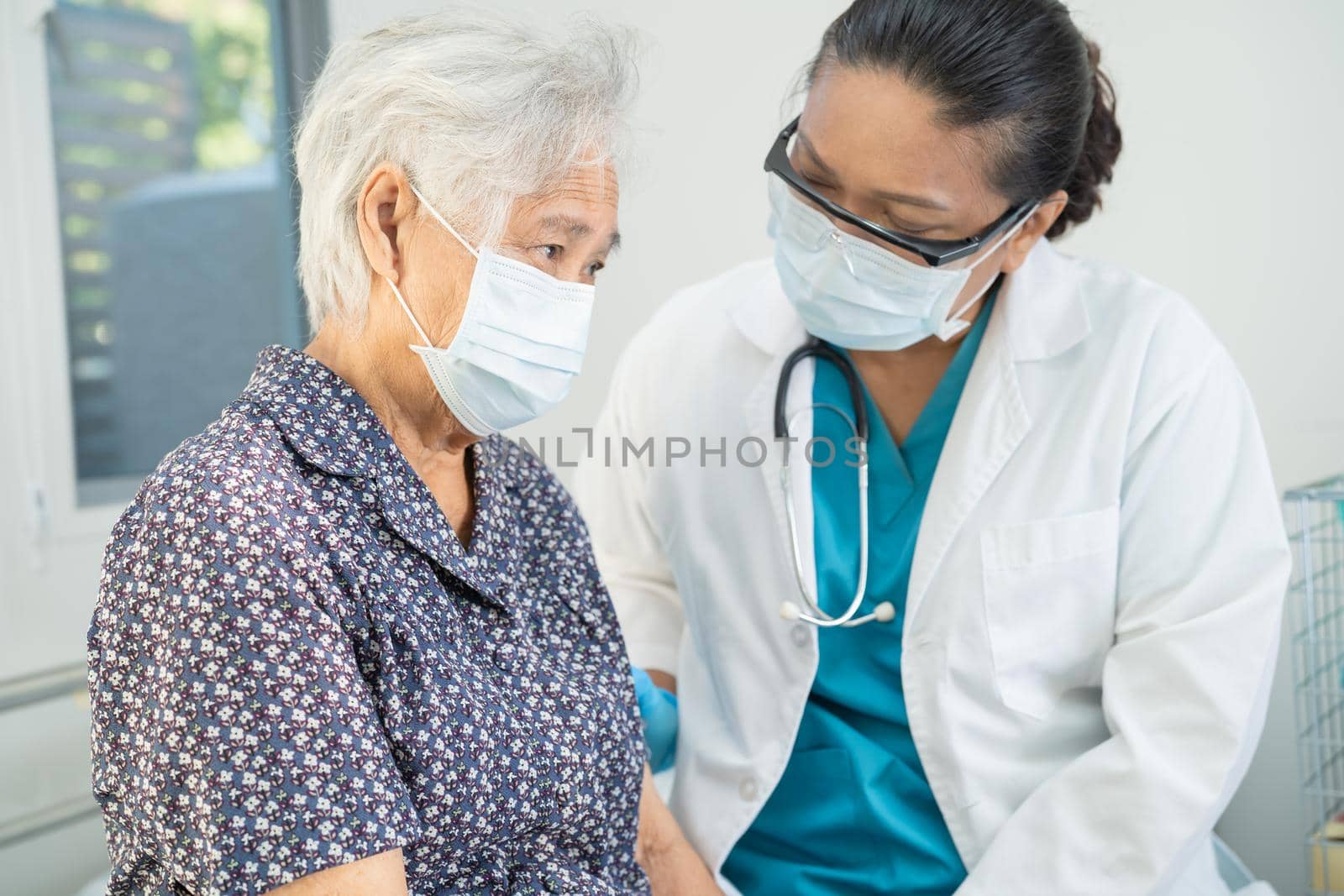 Asian doctor wearing face shield and PPE suit new normal to check patient protect safety infection Covid 19 Coronavirus outbreak at quarantine nursing hospital ward. by pamai