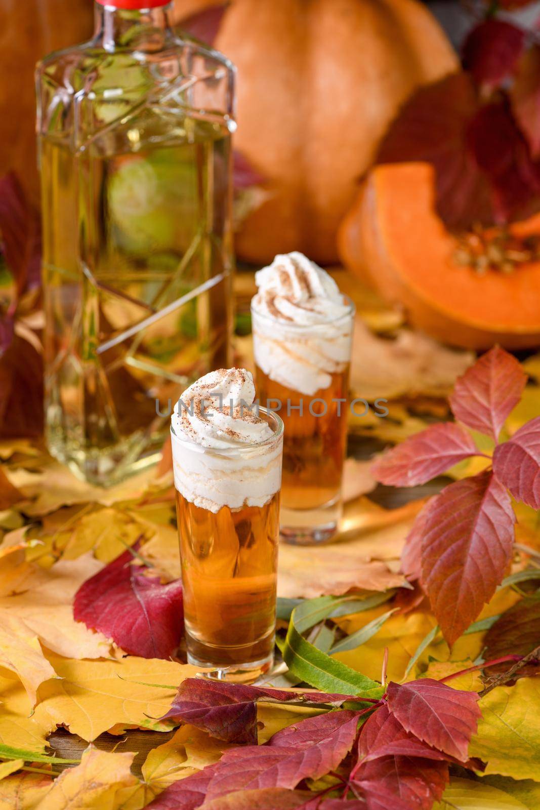 Two vodka with cream cinnamon pumpkin pie shooters in shot glasses. These drinks are easy to make and perfect for fall. Try these boozy drinks at your Halloween or Thanksgiving party