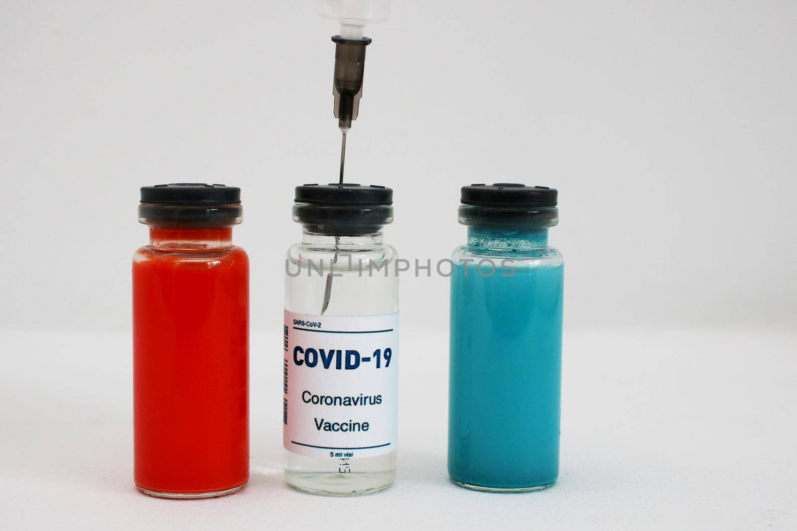 Medical Ampoules And Syringe. 3 ampoules with medicine and a syringe inserted. White, red and blue ampoule with vaccine.