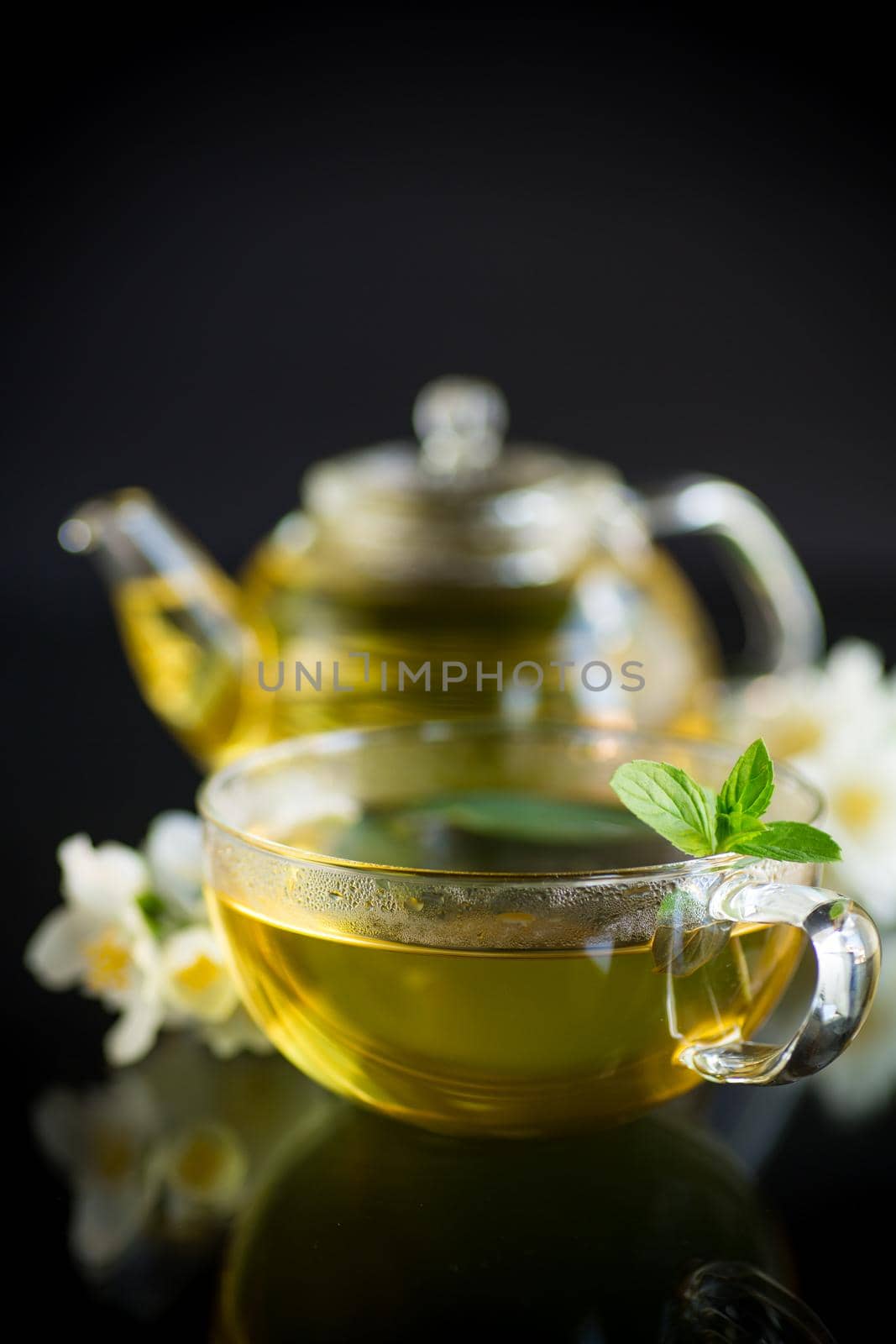 Composition with cup of jasmine tea and flowers isolated on black background