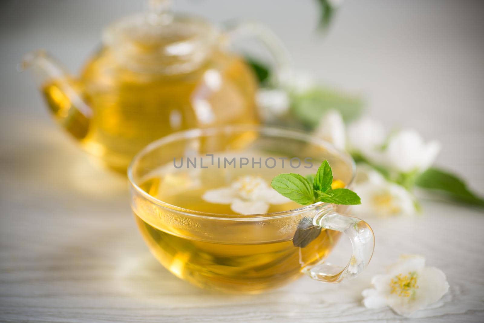 Composition with cup of jasmine tea and flowers on light background