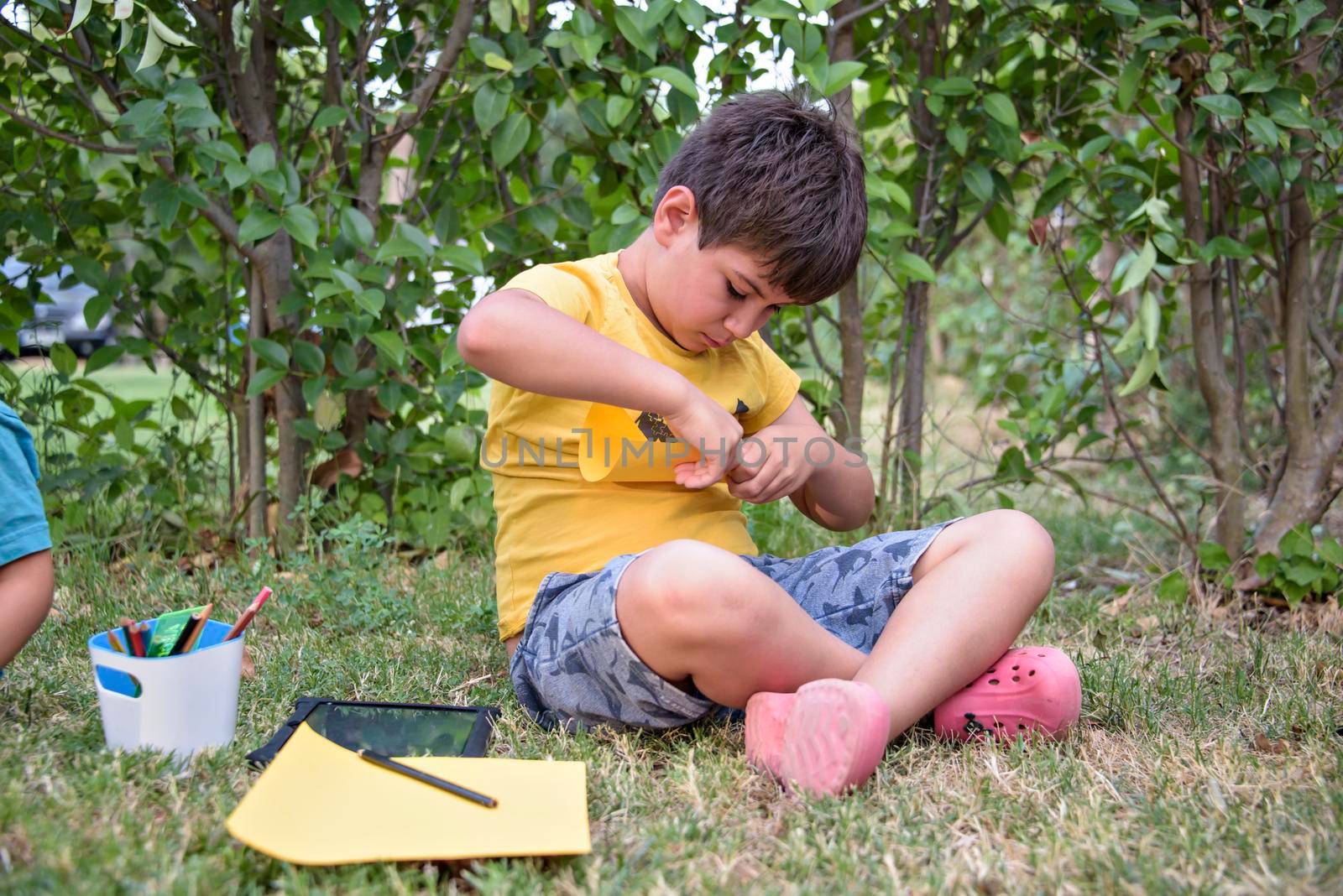 Kid draws in park laying in grass having fun on nature background