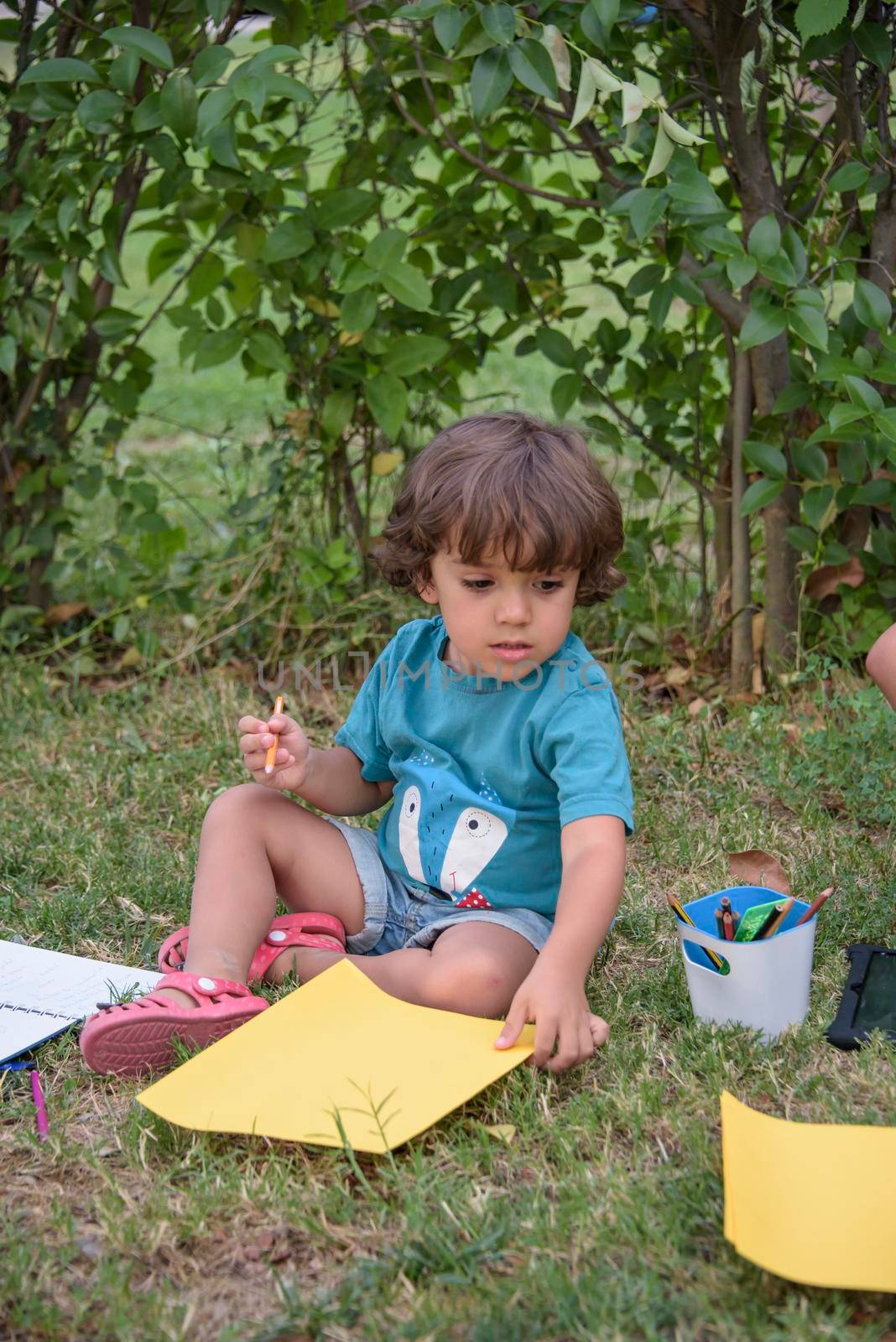 Little boy are using a magic pen to draw pictures in a book on a wooden table in park With face expression of determination