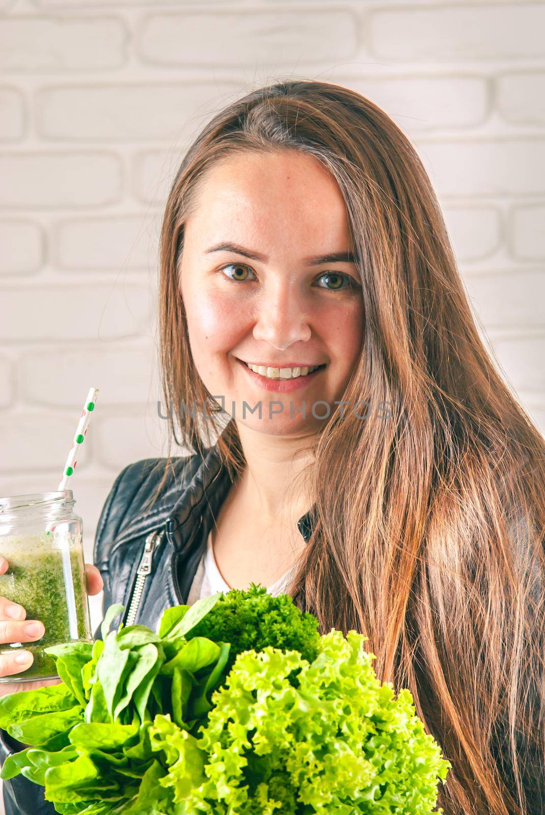 beautiful young smiling woman is drinking green detox shake . High quality photo