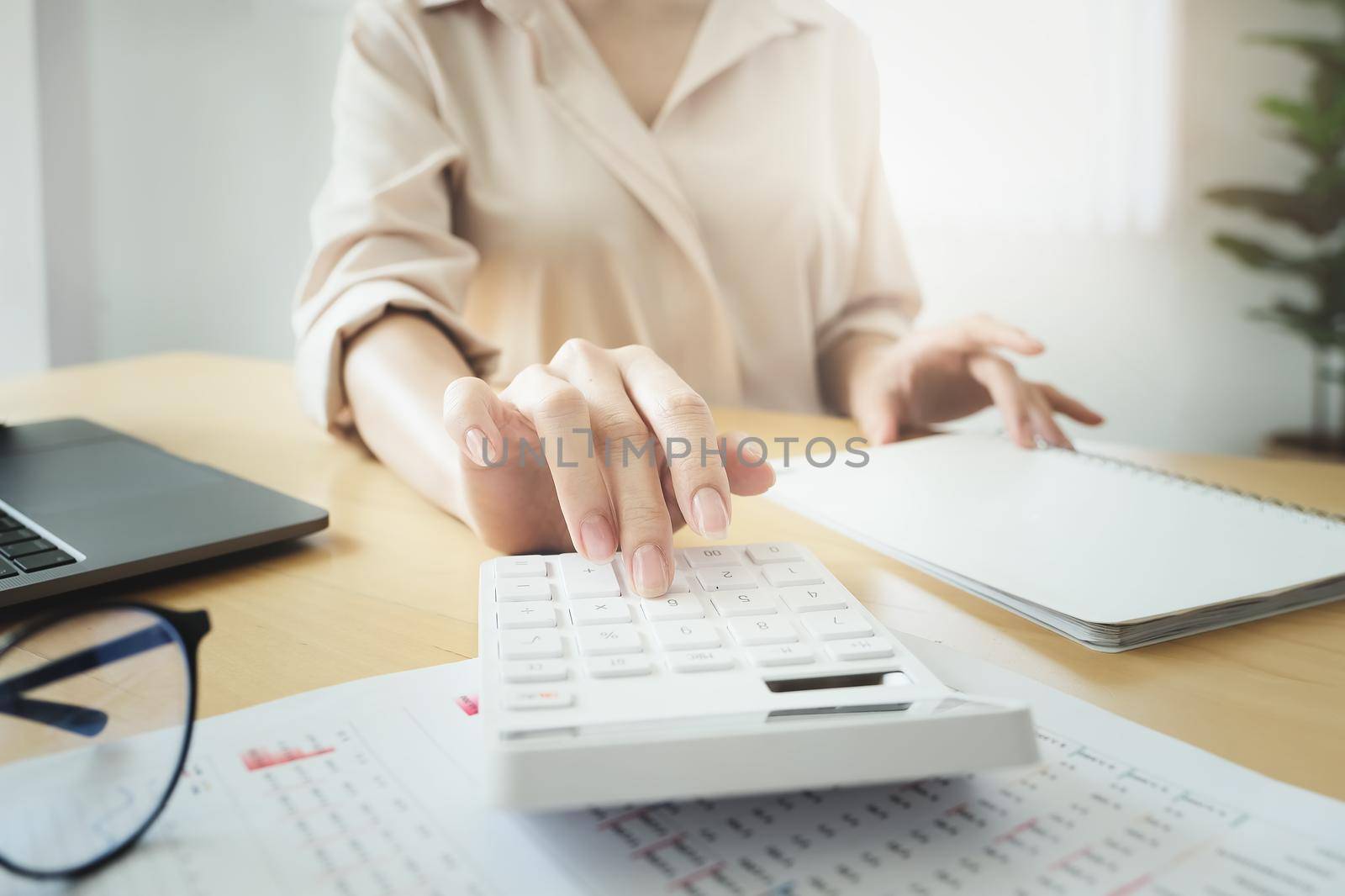 Business woman using calculator to review balance sheet annual using document and laptop computer to calculating budget. audit and Check integrity before investment concept. by Manastrong
