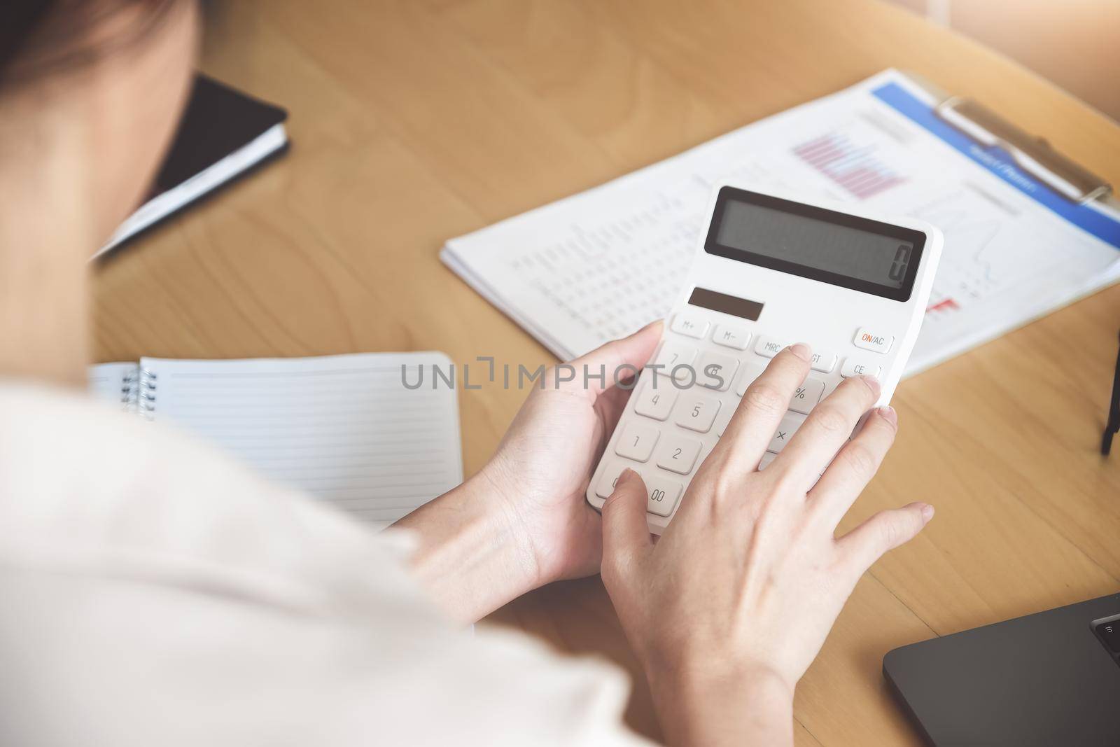 Business woman using calculator to review balance sheet annual using document and laptop computer to calculating budget. audit and Check integrity before investment concept