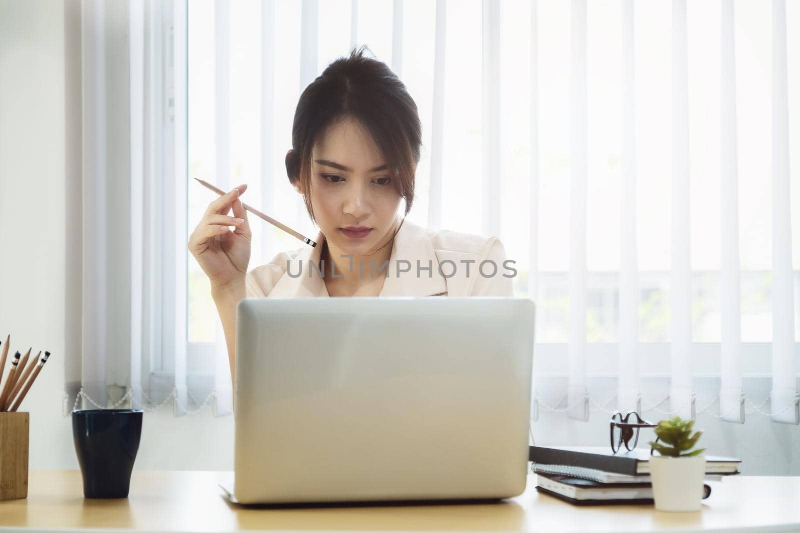 new normal, a businesswoman uses a computer to work for a company Via the internet on your desk at home. by Manastrong