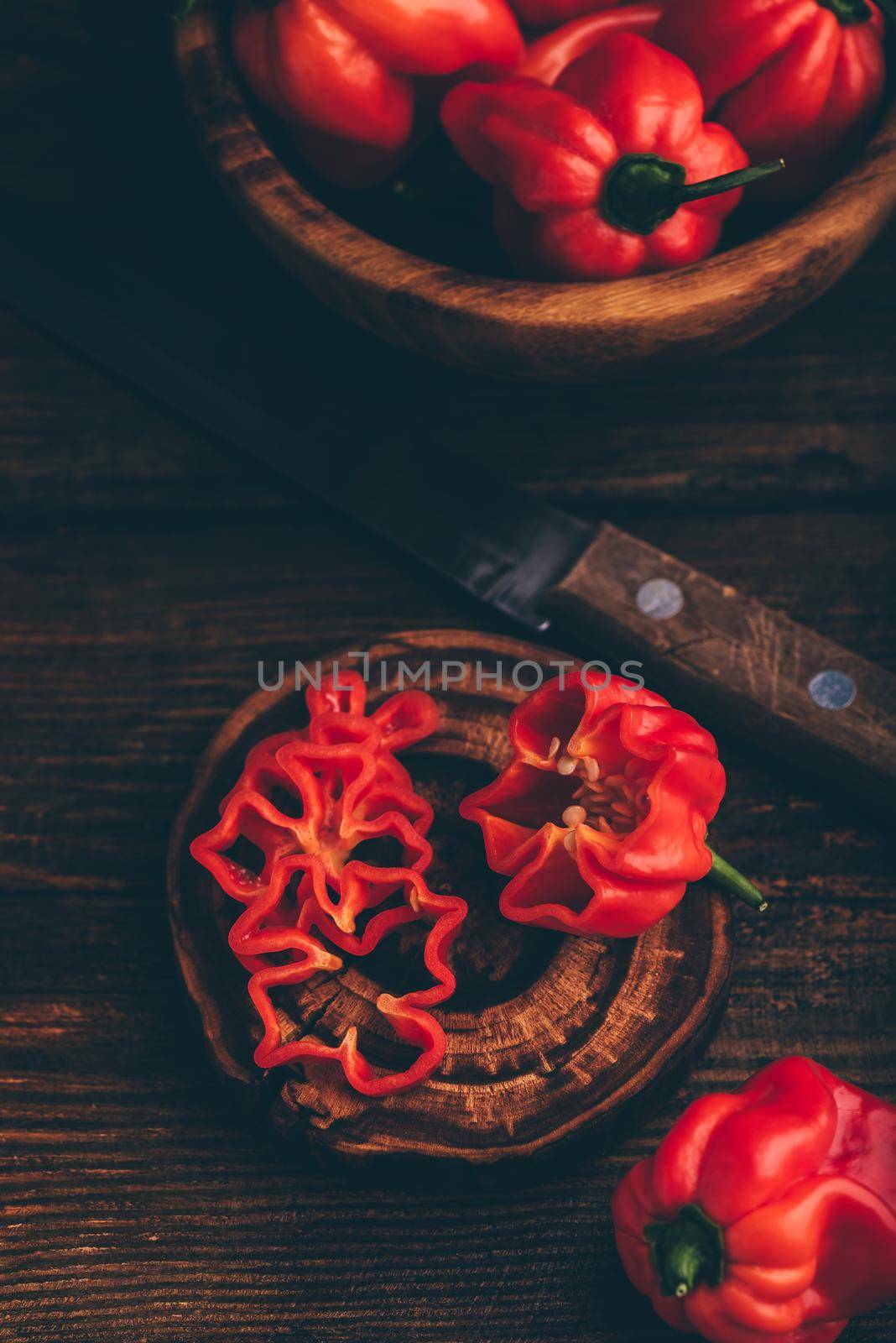 Red Habanero Chili Peppers and One Sliced on a Dark Wooden Surface