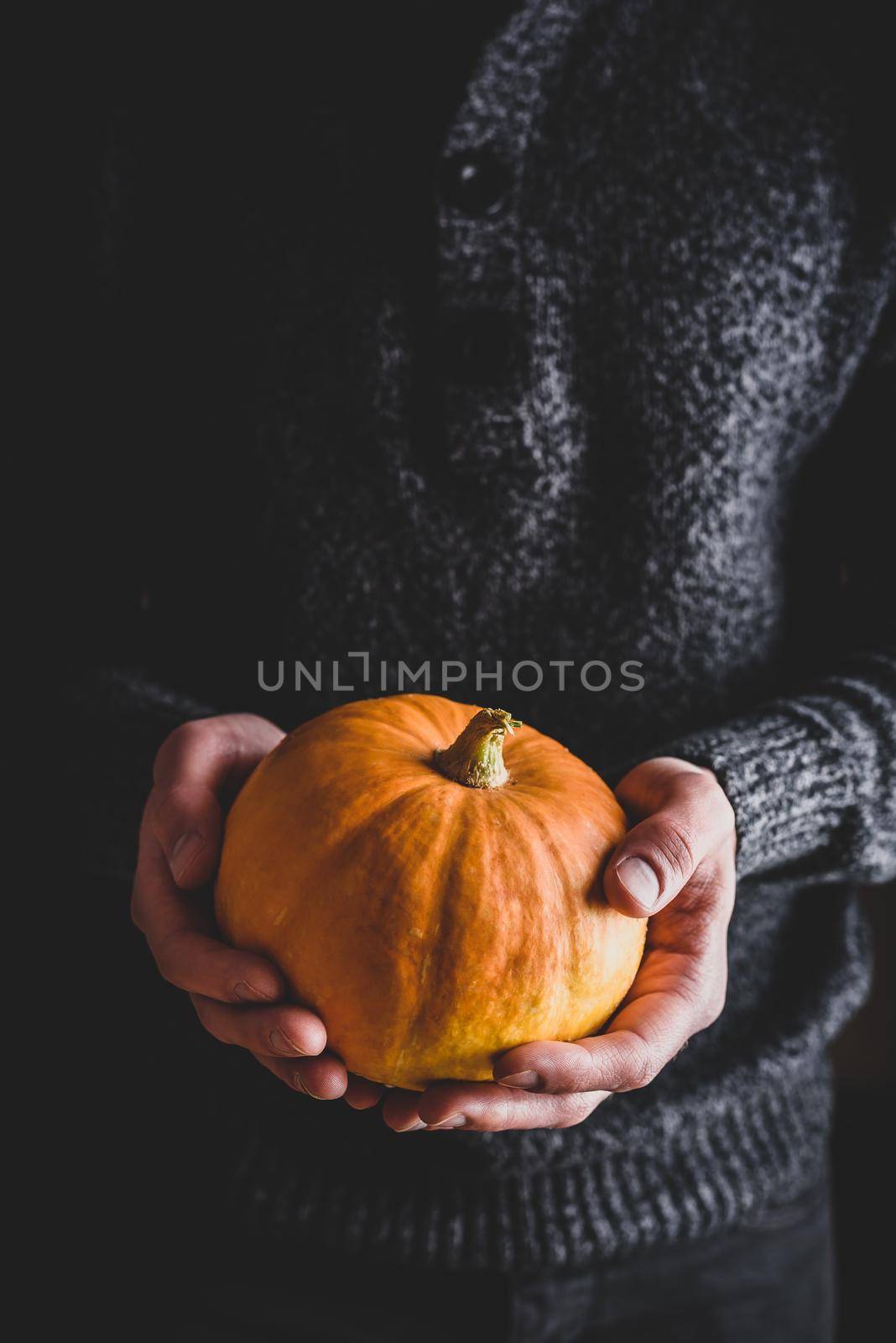 Man holding small ripe pumpkin in hands