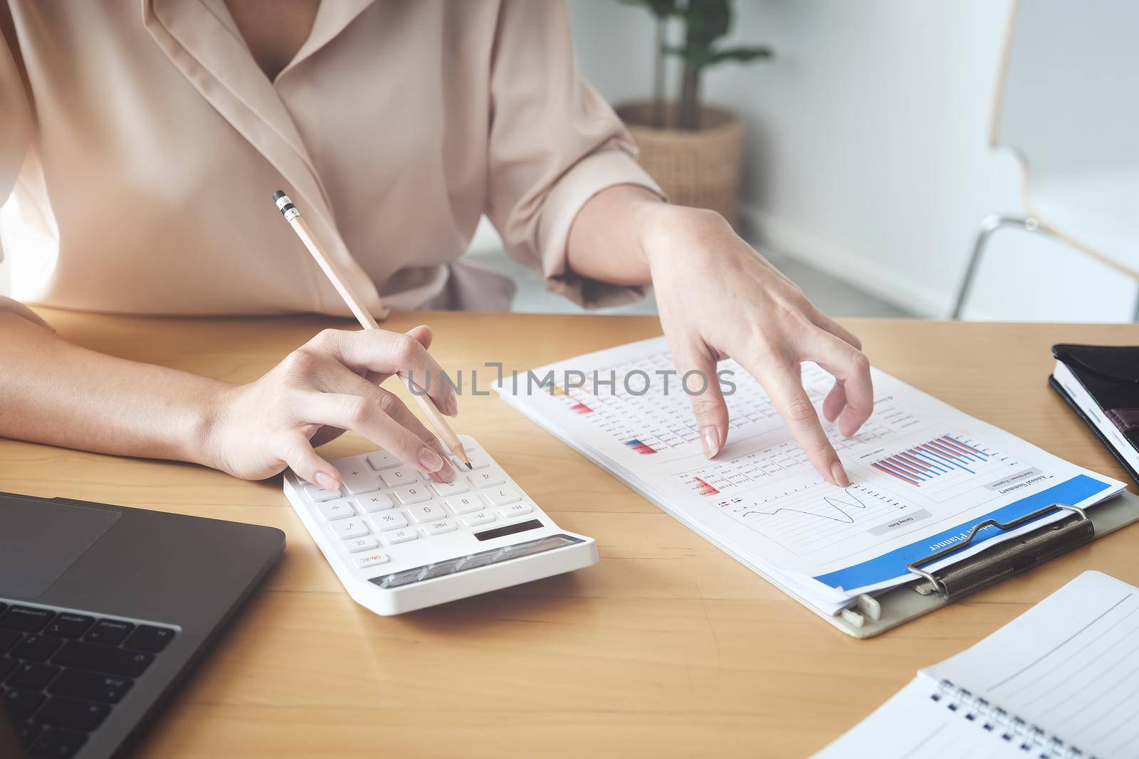 Business woman using calculator to review balance sheet annual using document and laptop computer to calculating budget. audit and Check integrity before investment concept.