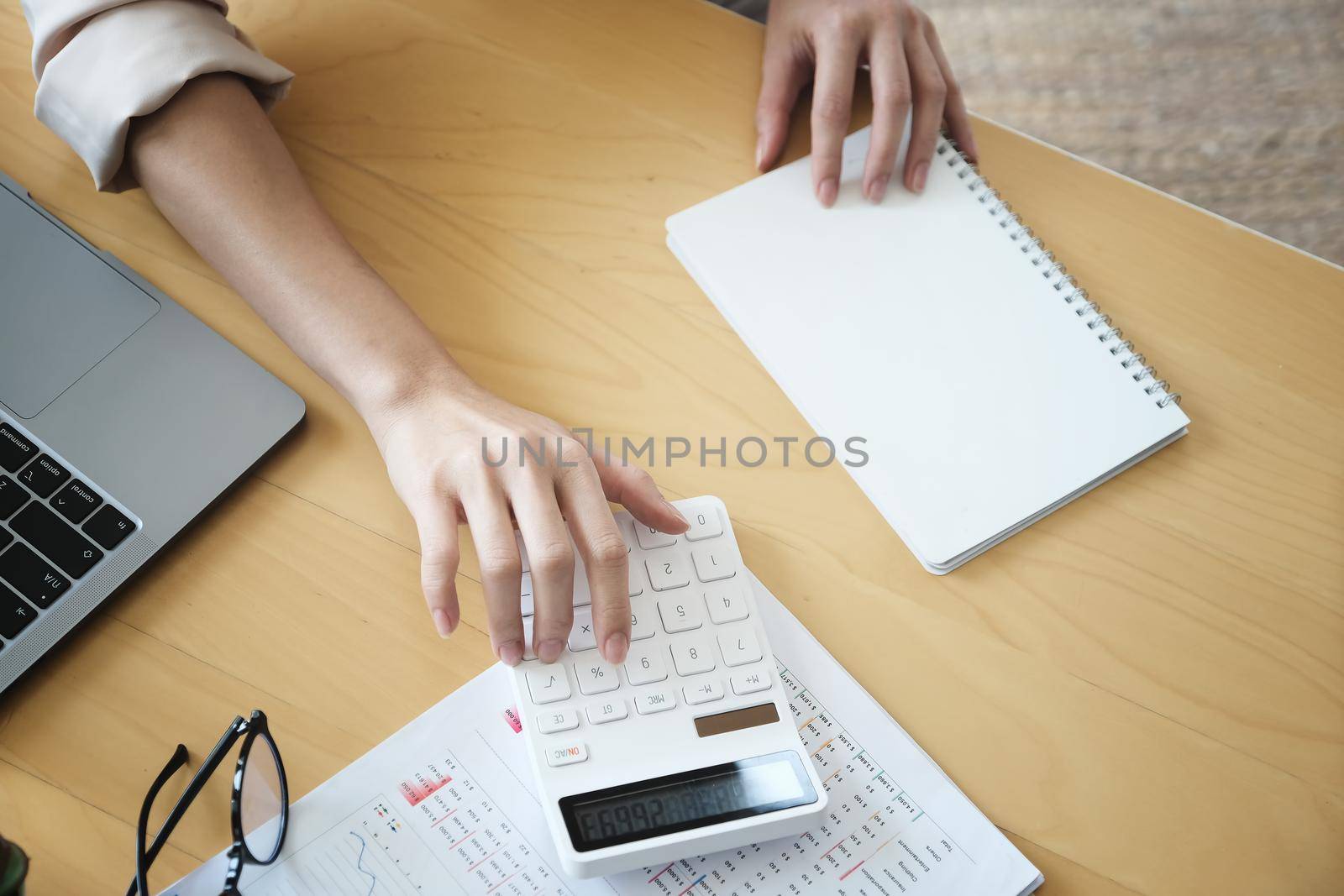 Business woman using calculator to review balance sheet annual using document and laptop computer to calculating budget. audit and Check integrity before investment concept. by Manastrong