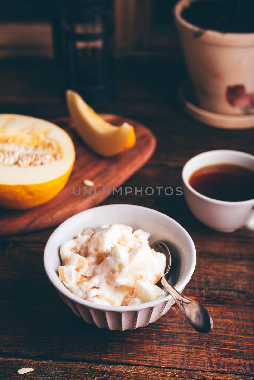 Spoon in Homemade Ice Cream Mixed with Melon and Covered with Berry Syrup in Bowl