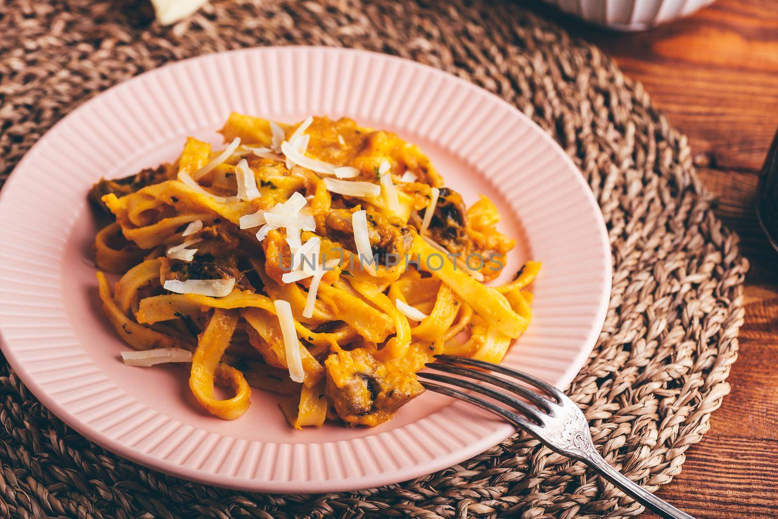Tagliatelle Pasta with Creamy Pumpkin Sauce and Champignons Garnished with Grated Parmesan Cheese