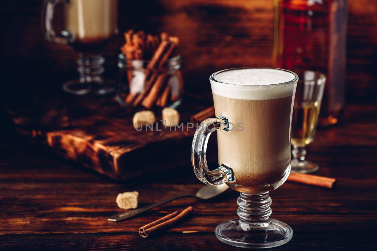 Irish coffee with cinnamon on wooden surface