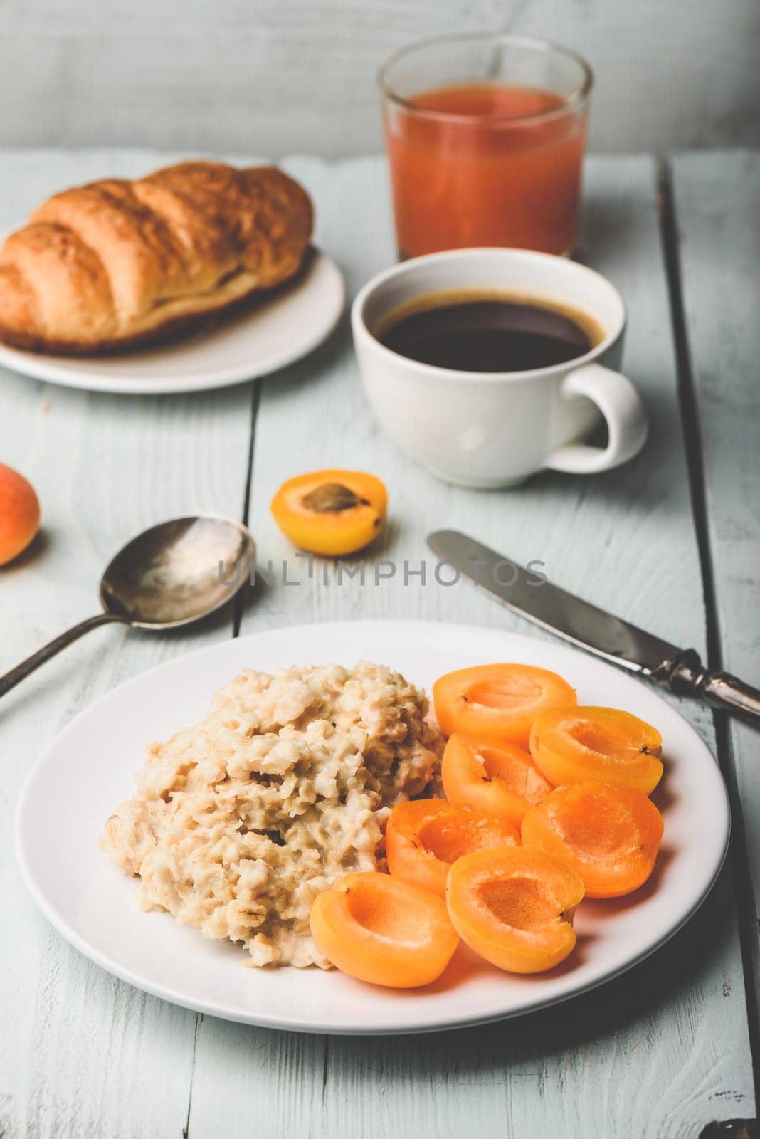 Breakfast set. Porridge with sliced apricot, cup of coffee, glass of grapefruit juice and croissant