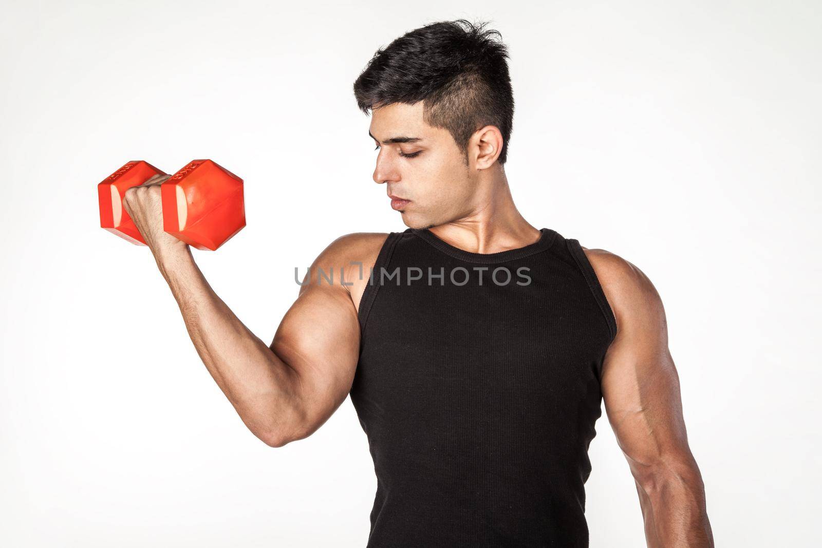 Portrait of young adult brunette sportsman wearing black sleeveless T-shirt raising hand with dumbbell, doing sport exercises for biceps. Indoor studio shot isolated on white background.