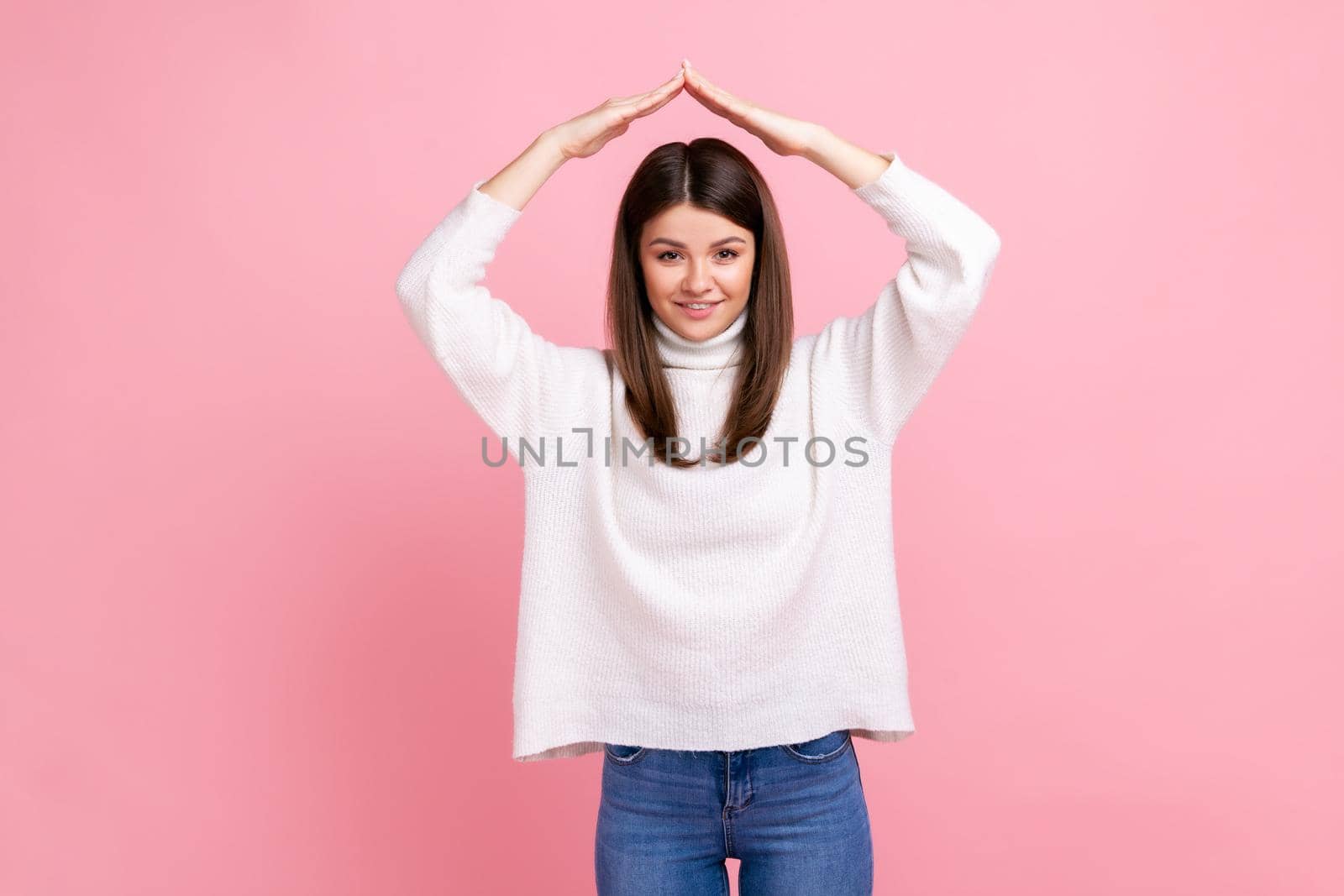 Woman making roof of hands above head looking at camera with toothy smile, feeling herself in safety by Khosro1