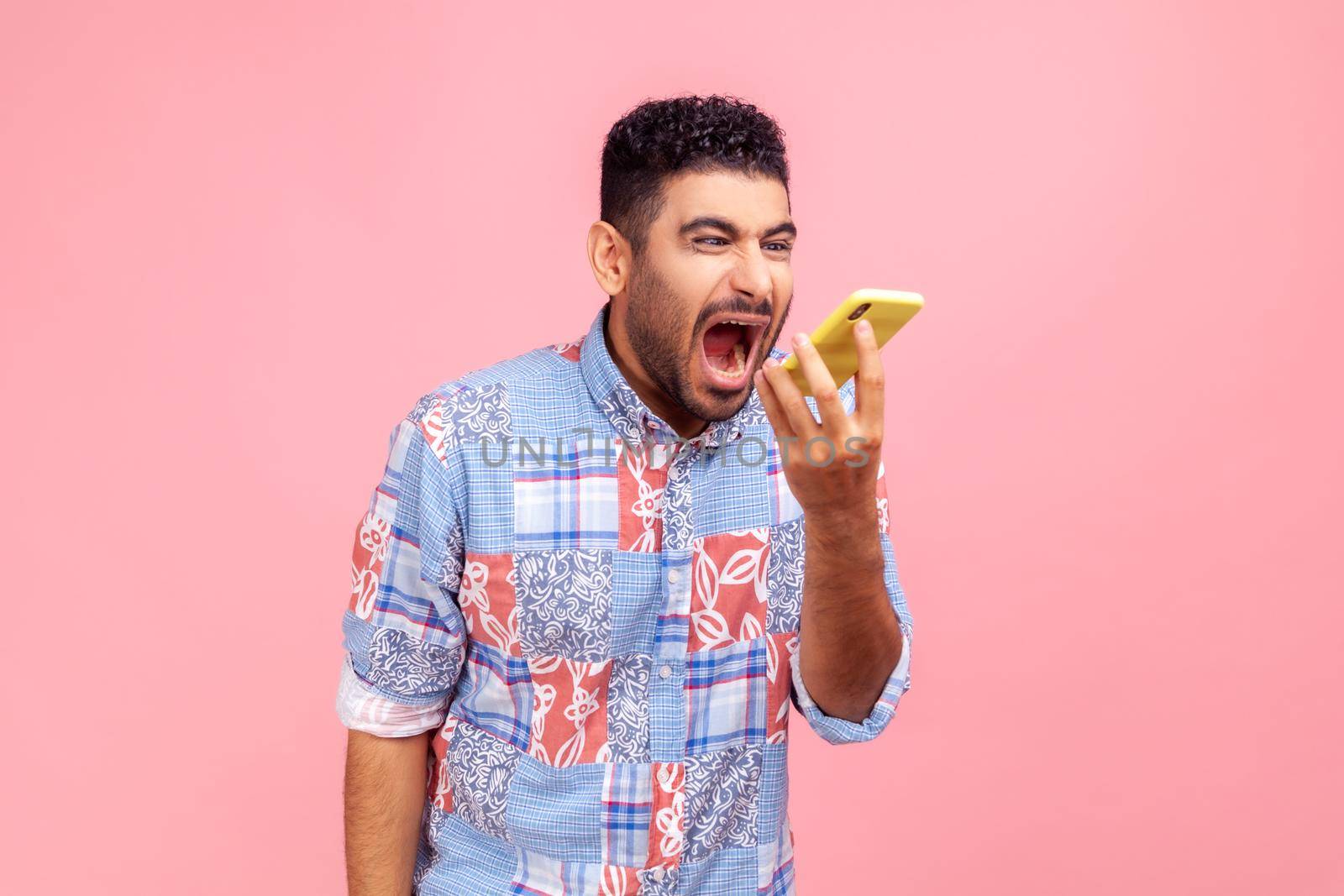 Portrait of angry mad man with beard in blue casual shirt loudly screaming talking phone, leaving voice message with furious aggressive expression. by Khosro1